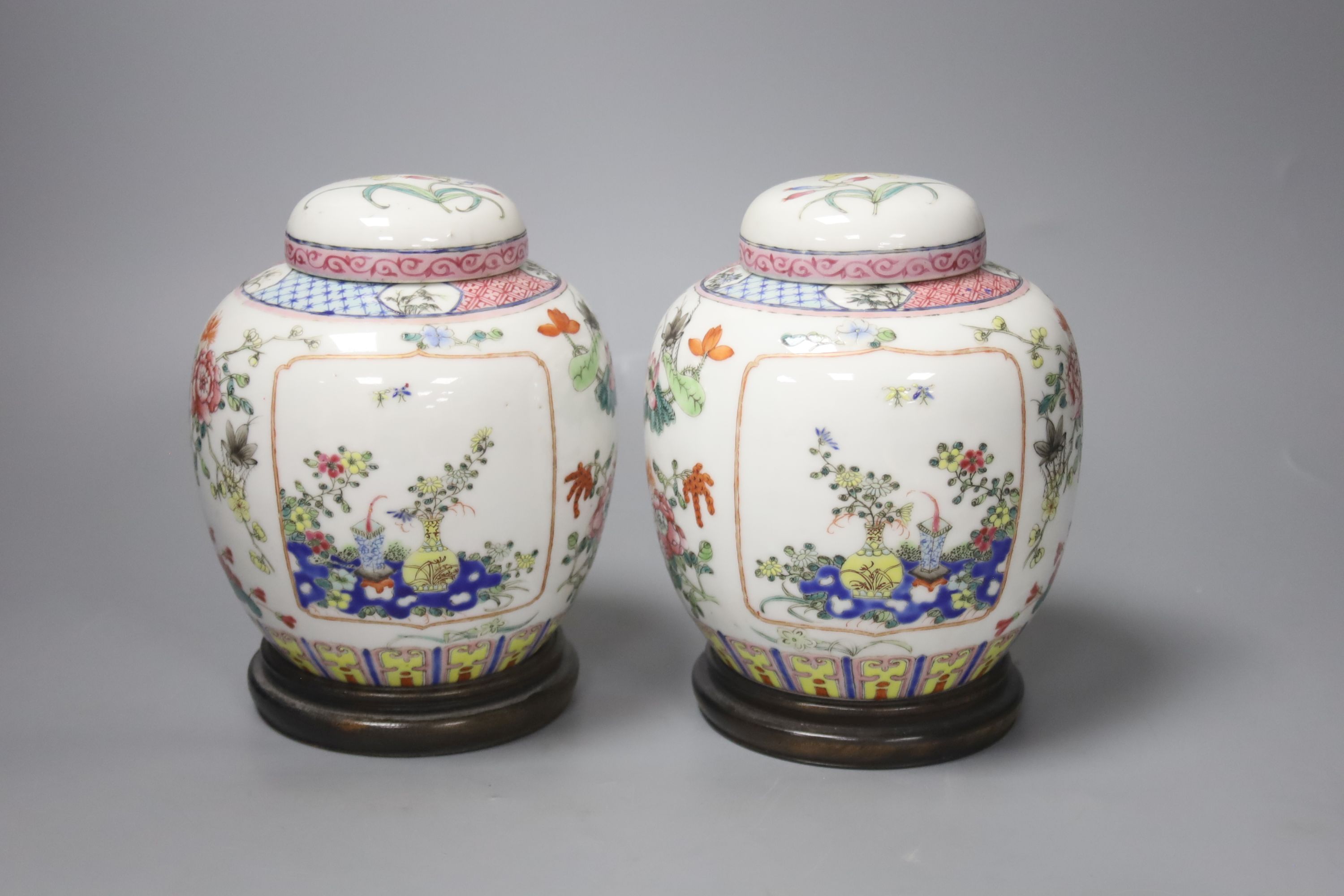 A pair of Chinese famille rose jars and covers, late 19/early 20th century, 15.5cm, on hardwood stands